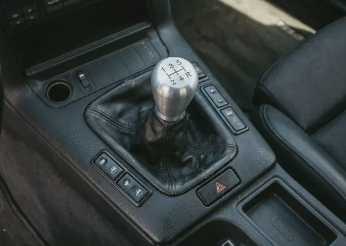 High-quality short throw shifter installed in a daily-driven manual car close-up of an aftermarket short throw shifter assembly installed in a street car center console