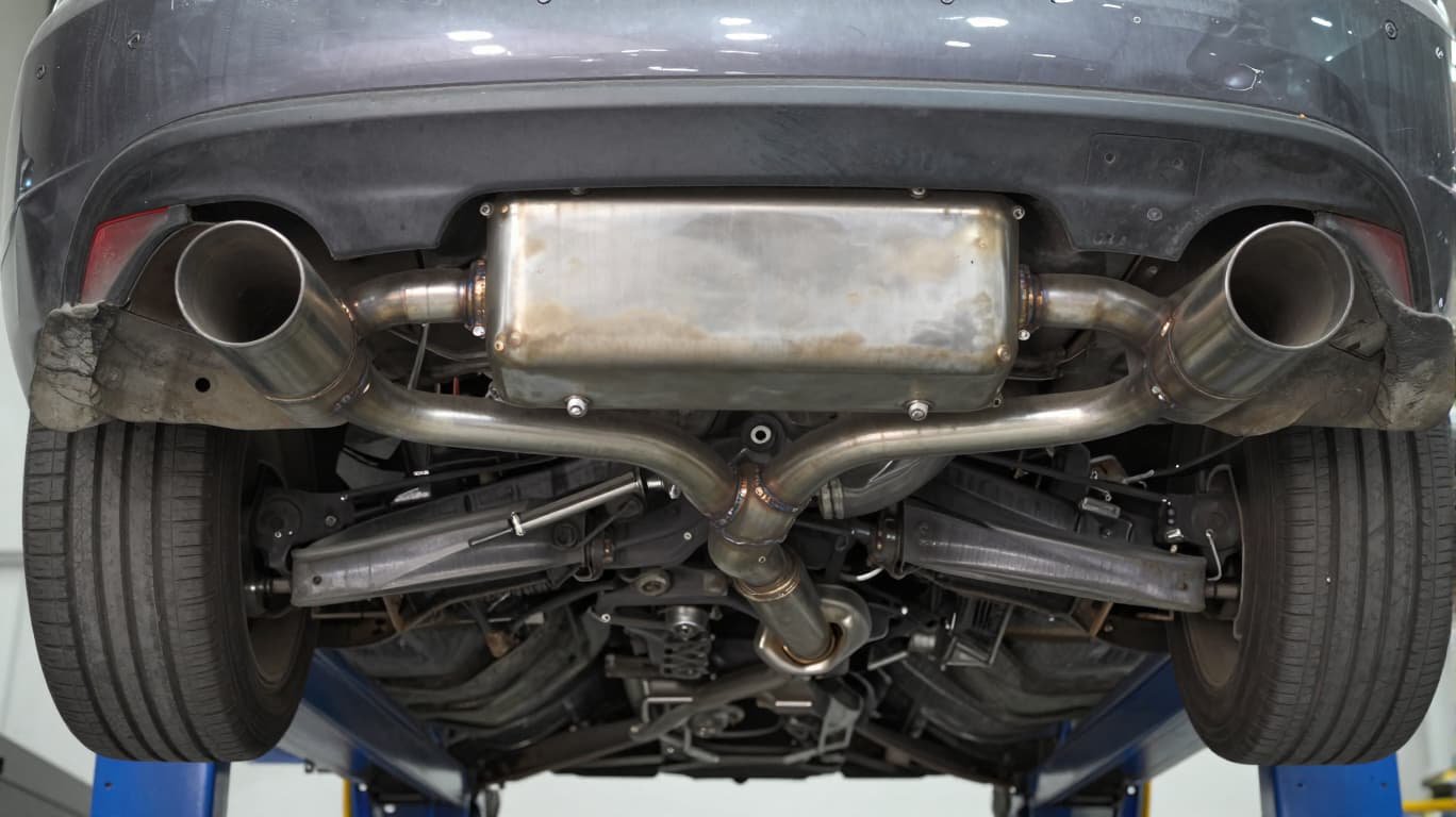 quality stainless steel exhaust system installed under a street car showing resonator and muffler