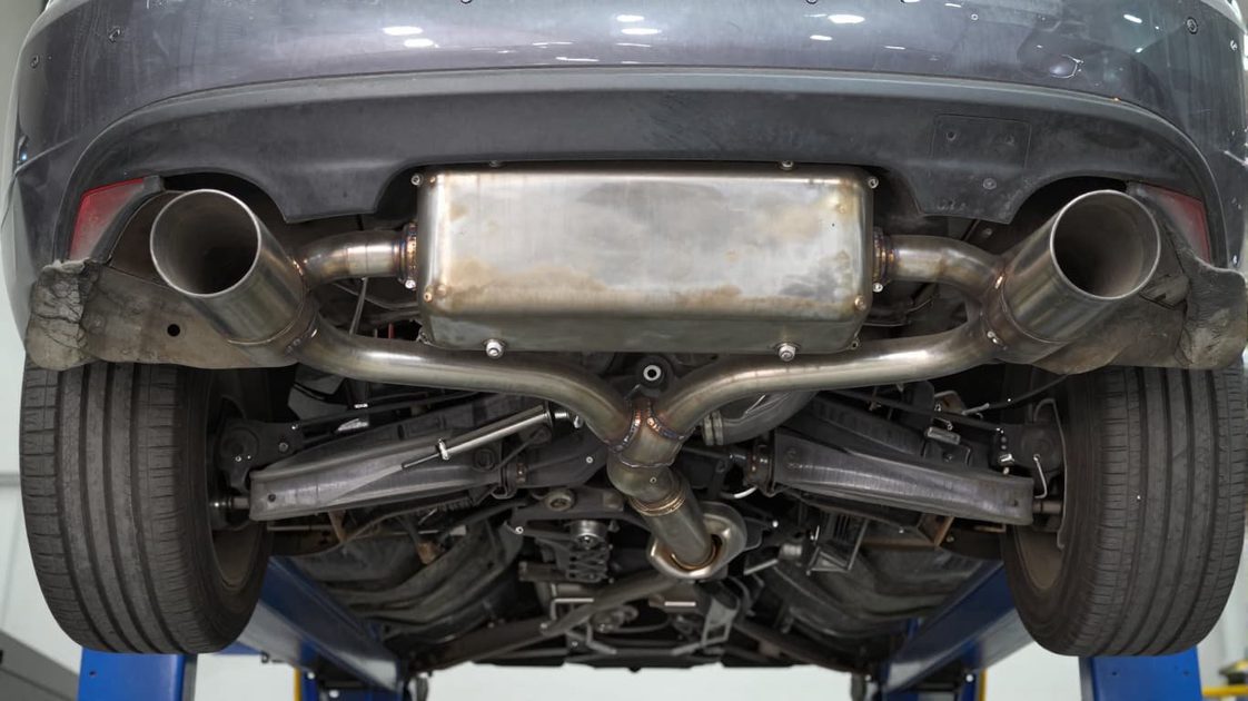 quality stainless steel exhaust system installed under a street car showing resonator and muffler