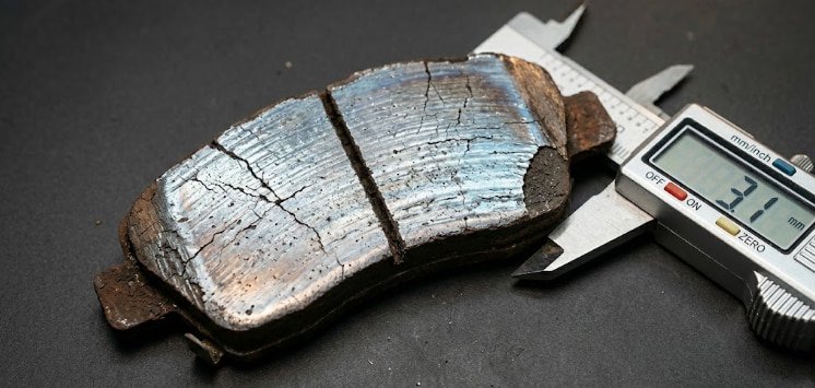 Worn factory brake pad showing glazing and edge cracking glazed and cracked factory brake pad removed from a performance street car